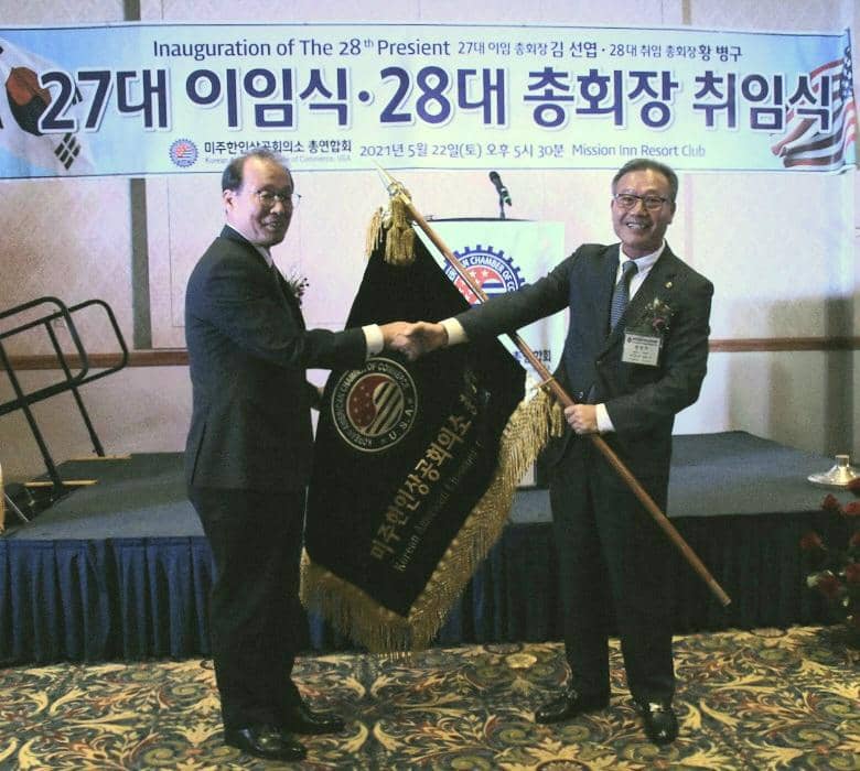 22일 열린 미주 한인상공회의소 총연합회장 이,취임식에서 김선엽(왼쪽) 27대 회장이 황병구 신임회장에게 협회기를 이양하고 있다.